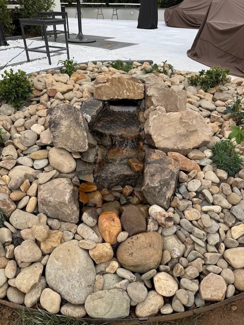 Small Bubbling Rock Water Feature by Alex's Lawnscape in Charlotte NC — Compact pondless bubbling rock water feature with stacked natural stones and river rock basin on a paver patio