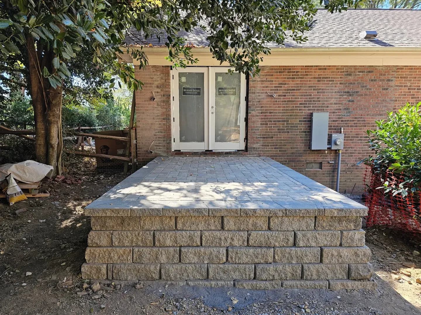 Raised Patio Entry at French Doors by Alex's Lawnscape in Charlotte NC — Raised paver patio with retaining wall block base at a brick home with French doors