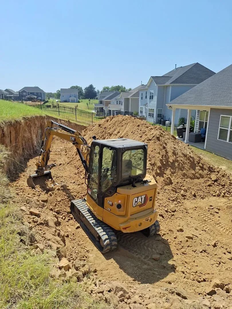Excavation for Major Hardscape Project by Alex's Lawnscape in Charlotte NC — CAT mini excavator handling a large residential backyard excavation — showing the scope of site preparation that goes into premium hardscape installations