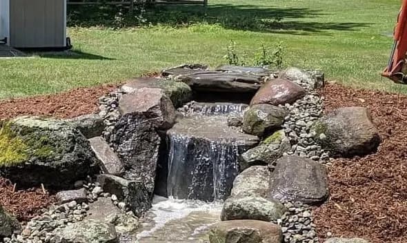 Boulder Water Feature by Alex's Lawnscape in Charlotte NC — Backyard water feature with natural boulders cascading from an upper basin into a lower pool